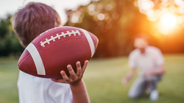 A group of friends playing a spirited game of football in a backyard, with laughter and camaraderie in the air.