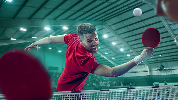 Two players engaged in a fast-paced table tennis match, with the ball mid-air and expressions of concentration on their faces.