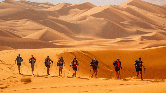 Runners traversing a vast expanse of sand under the scorching Sahara sun in the Marathon des Sables